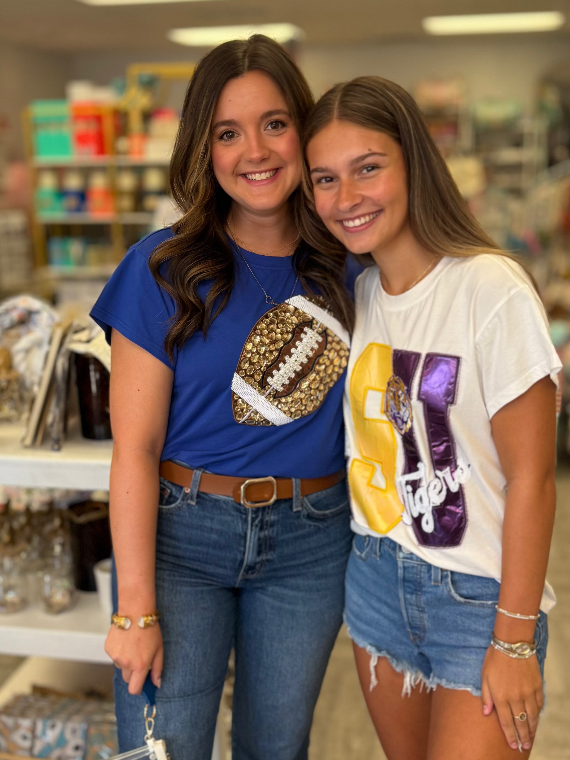 Two women posing for a photo in a store with shelves and products in the background.